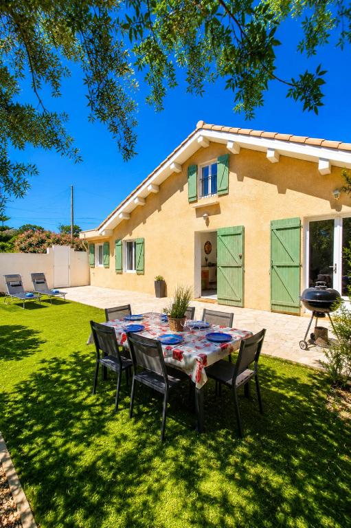 a table and chairs in the yard of a house at Villa Papillons Narbonne 'Jardin & Clim' 'Proche Centre & Plages' in Narbonne