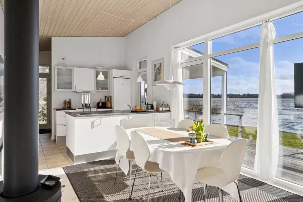 a kitchen with white cabinets and a table and chairs at Luxury Lakeside Retreat in Ringsted