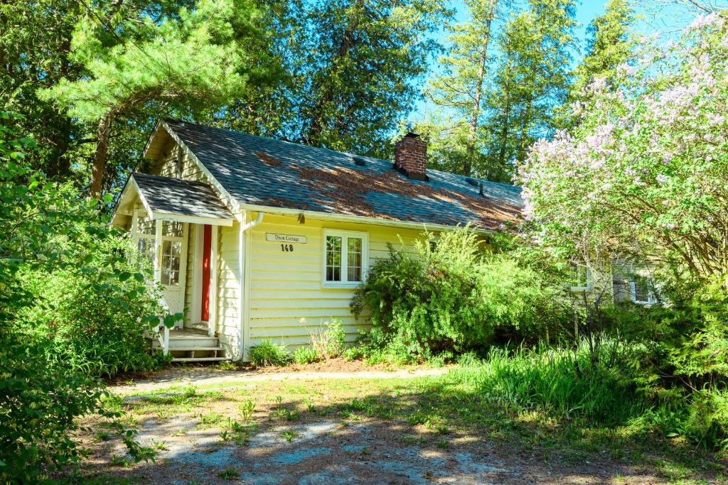 a small yellow house in the middle of trees at 148 Divot Simcoe Cottage private Beach, Kayak in Georgina
