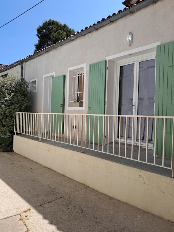 a house with green doors and a balcony at Chemin du vieux Puits in Surgères