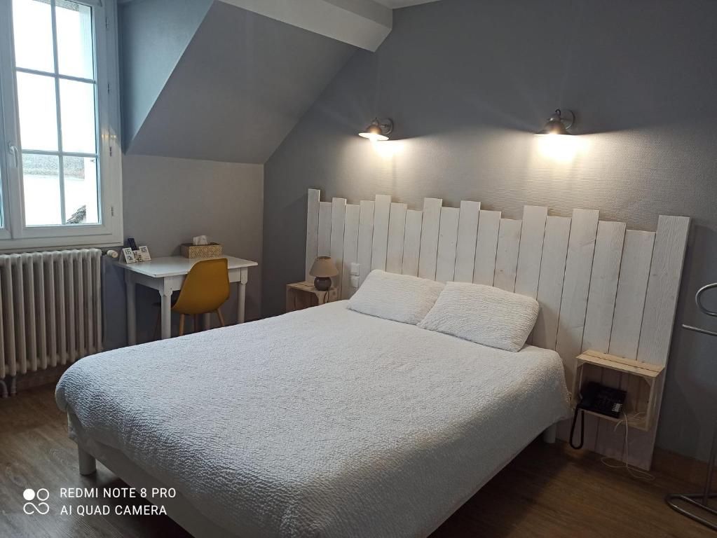 a bedroom with a large white bed and a desk at Logis Hôtel Auberge de la Gabrière in Lingé