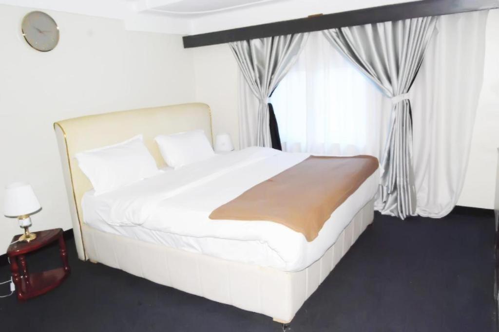 a white bed in a room with a window at KAA Highway Hotel in Mukono