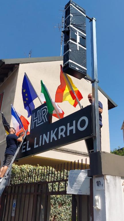 Eine Gruppe von Menschen steht mit Fahnen auf einem Straßenschild. in der Unterkunft Hotel Link Rho in Rho