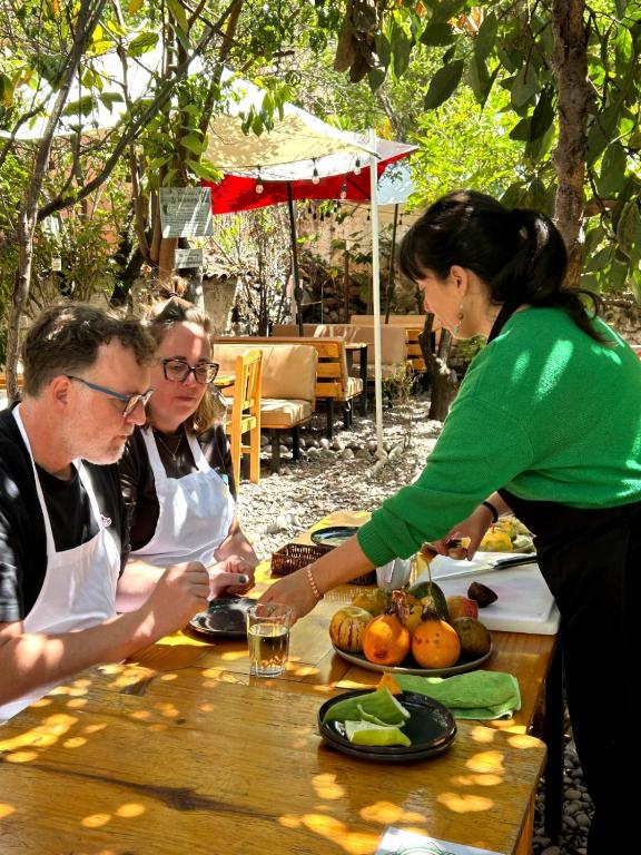 a woman reaching for a plate of food at a table at Pakakuna in Urubamba