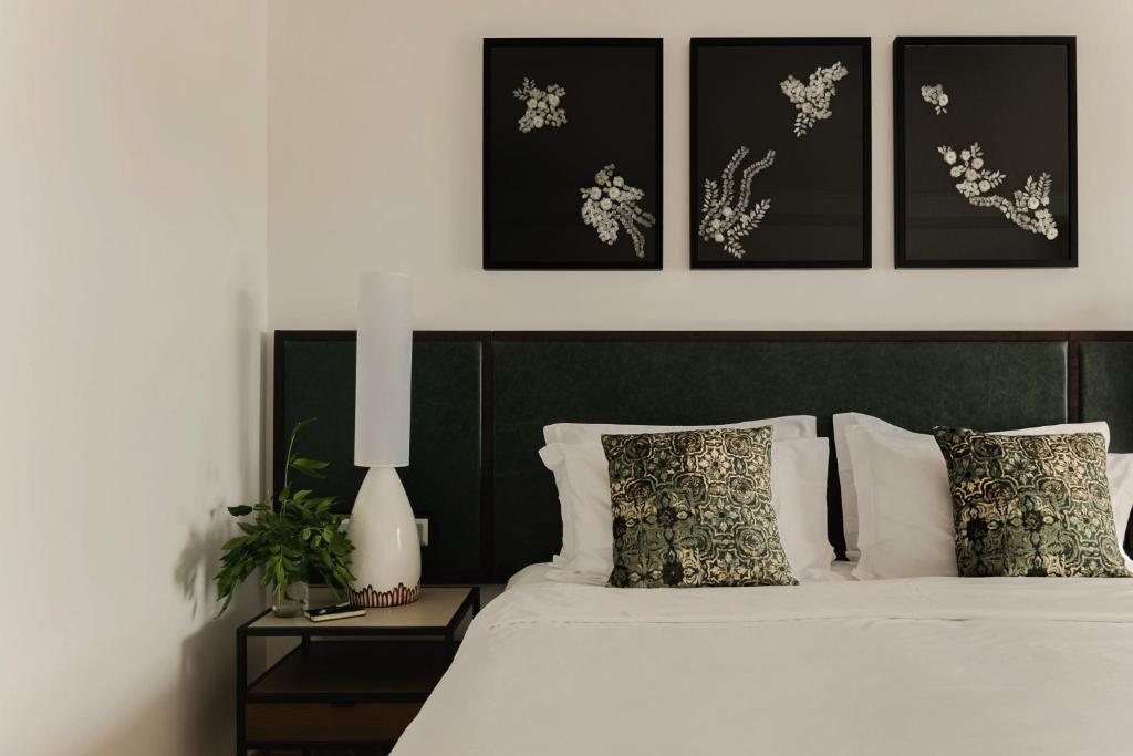 a bedroom with a white bed with four pictures on the wall at Hotel Ponta Delgada in Ponta Delgada