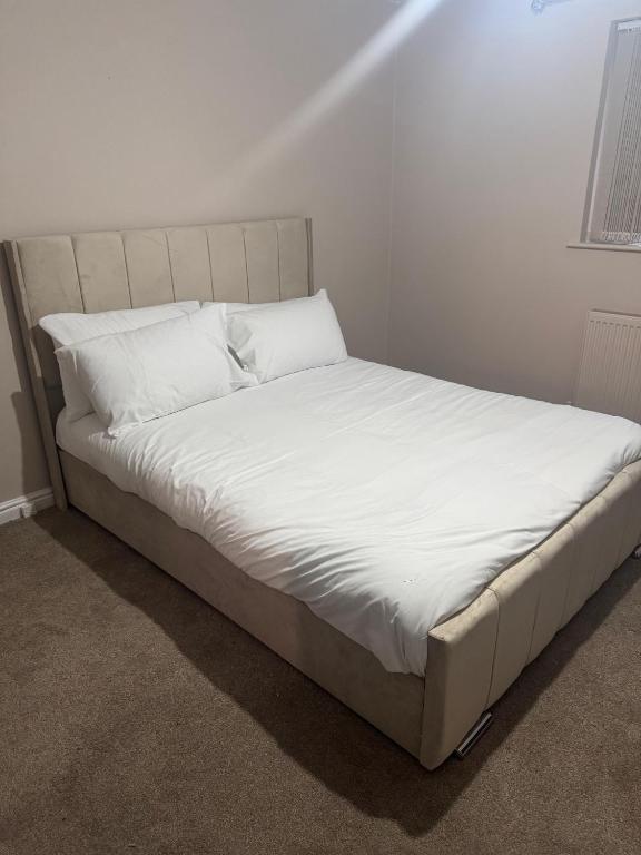 a bed with white sheets and pillows in a room at One Bedroom Spacious House in Cardiff