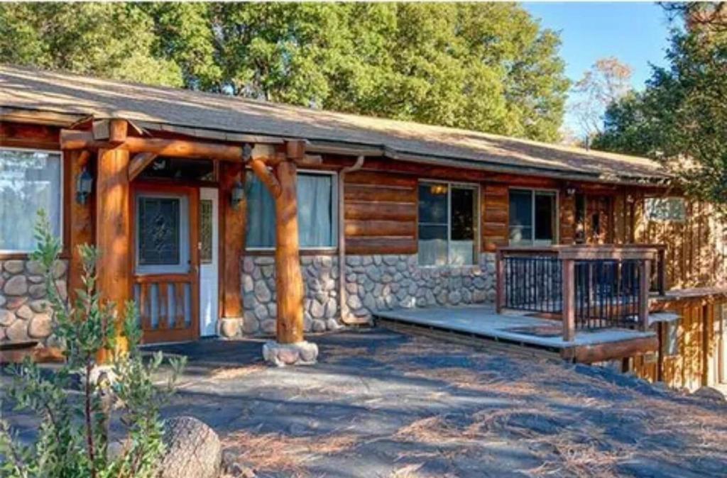 a log cabin with a porch and a stone wall at Wolf Den retreat on 20 acres in Julian