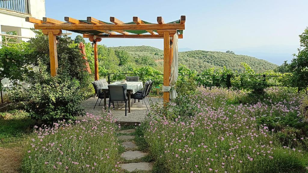 a table and chairs under a pergola in a garden at Mikros Paradisos Pelion in Áyios Vlásios