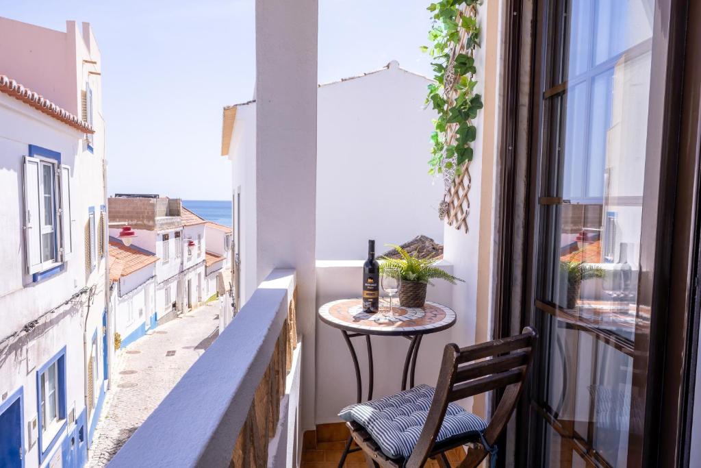 a balcony with a table and a bottle of wine at Casa Espadinha in Salema
