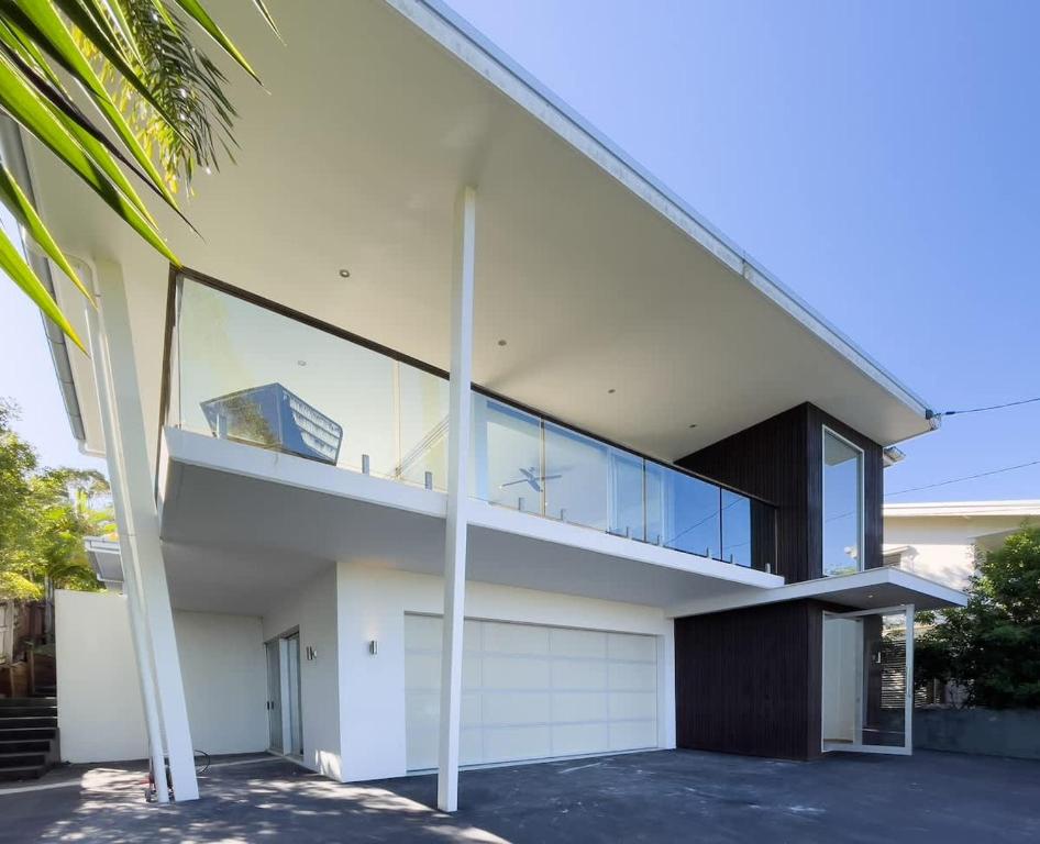 a large white house with a glass balcony at Stunning Views, Private Pool Near Hastings St in Noosa Heads