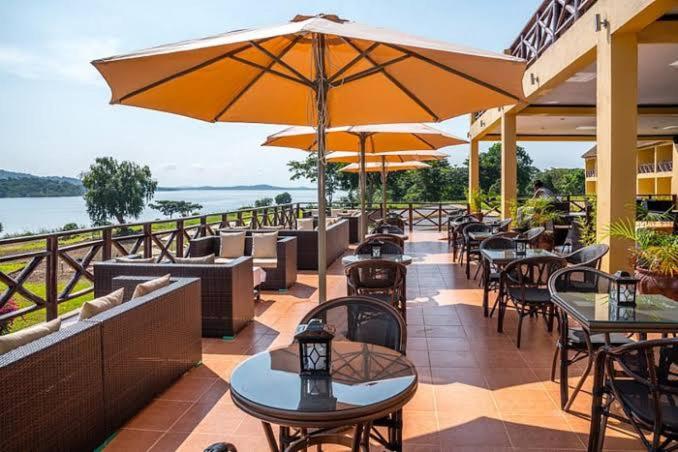 an outdoor patio with tables and chairs and umbrellas at KAA Highway Hotel in Mukono