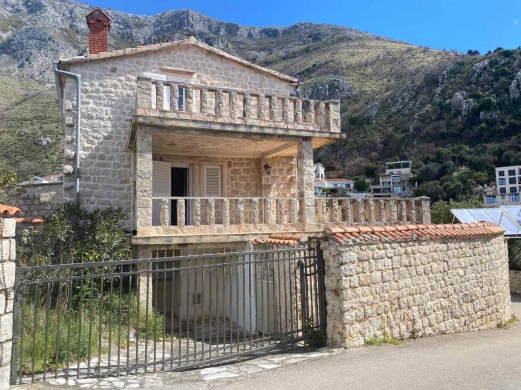 a stone house with a fence in front of a mountain at Stoun house in Reževići