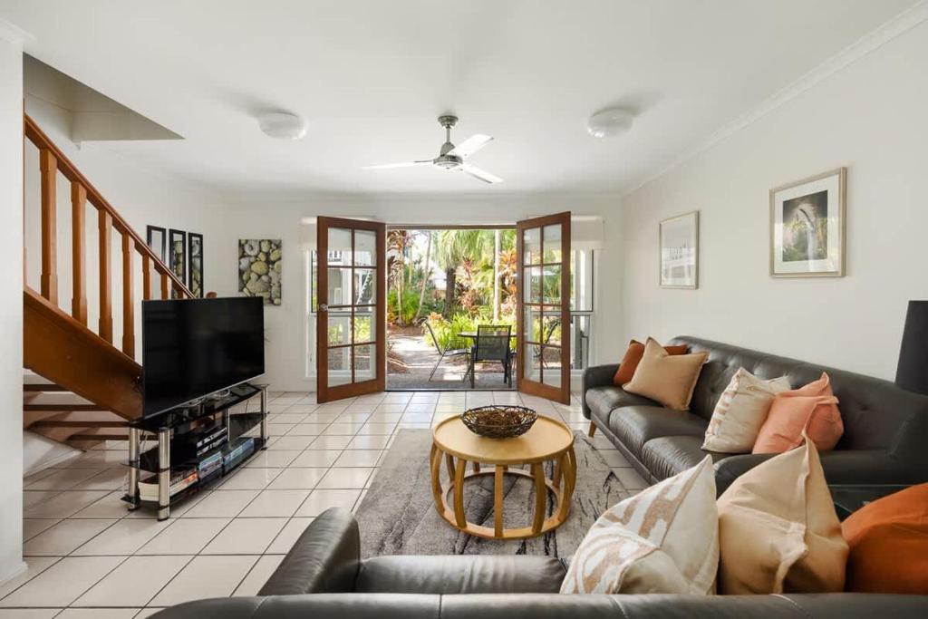 a living room with a couch and a tv at Riverside Rest on Noosa River in Noosaville