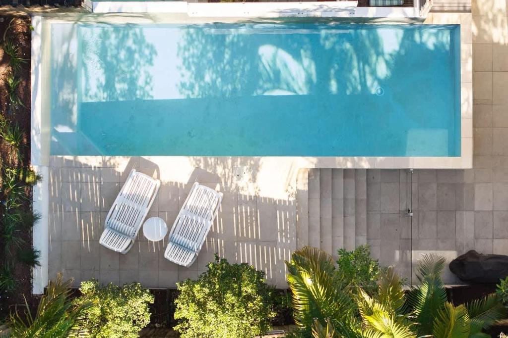 an overhead view of a swimming pool with three chairs at Townhouse with Private Magnesium Pool in Noosa Heads