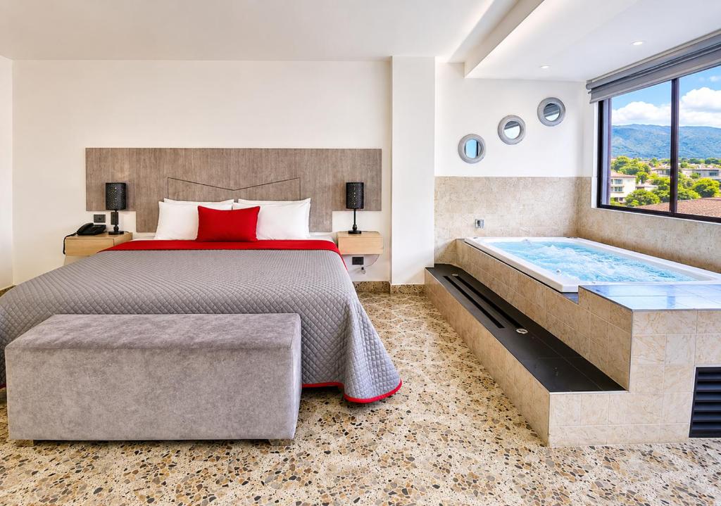 a bedroom with a large bed and a tub at Hotel Ofix - Laureles in Medellín