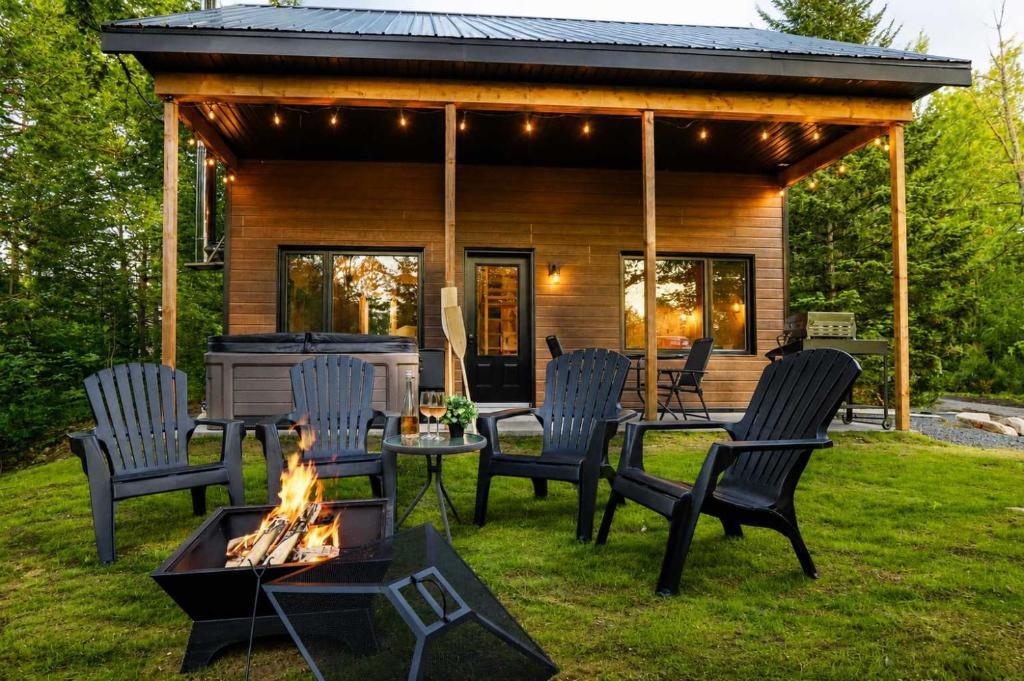 a group of chairs and a fire pit in front of a cabin at Le Colvert - Waterfront Cabin with Spa in Valcartier Station