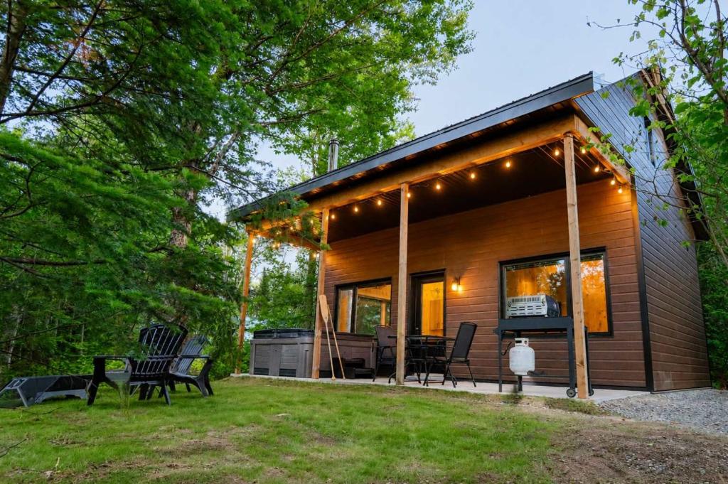 a log cabin with a grill and chairs in the yard at Le Geai Bleu - Waterfront Chalet with Spa in Valcartier Station