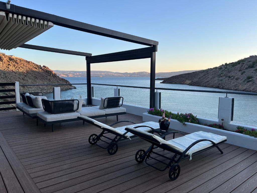 a deck with couches and chairs and a view of the water at Adventure House Cesarica in Cesarica