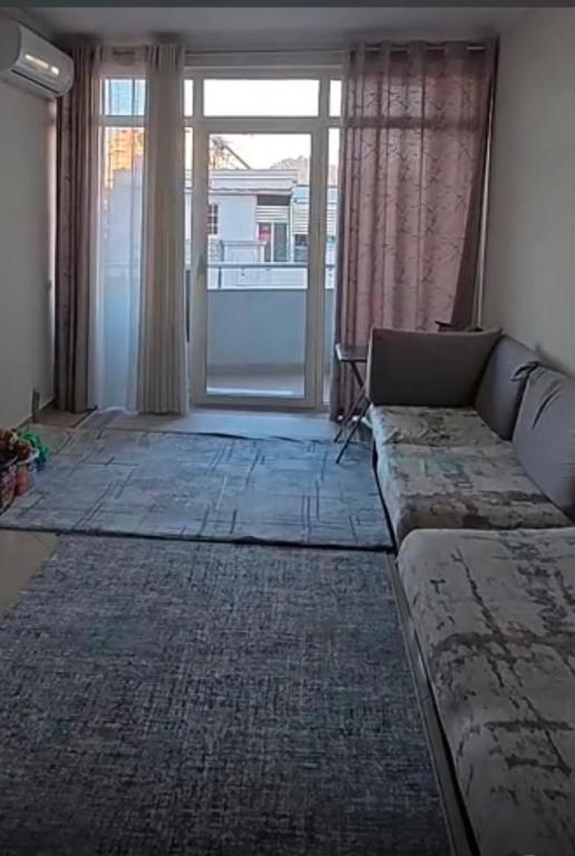 a living room with a couch and a large window at ApartamentAbiBank in Elbasan