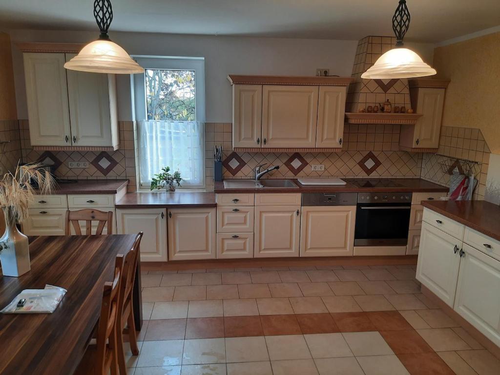 a kitchen with white cabinets and a table with chairs at Ferienwohnung Lilie in Pegau