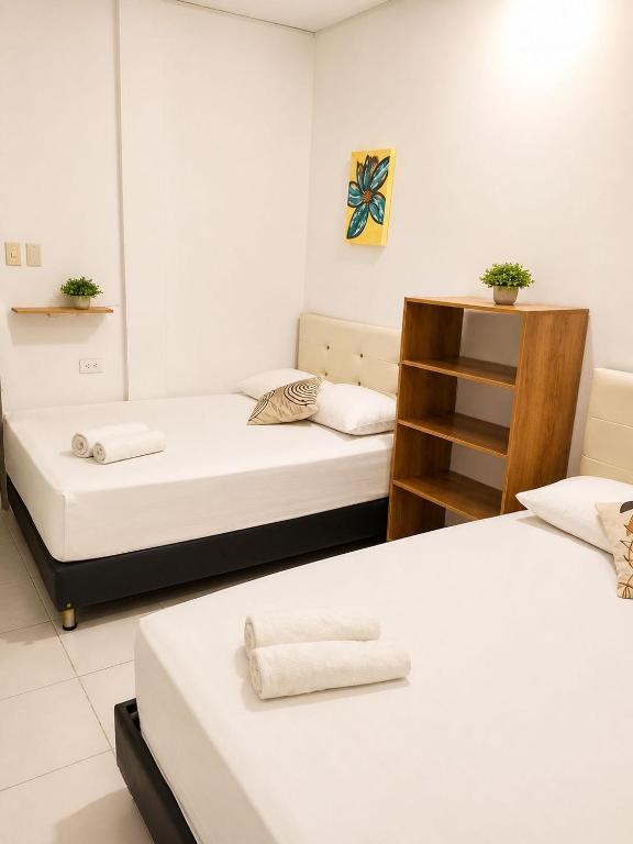 a room with two beds and a shelf at Hotel Riviera Central in Montería