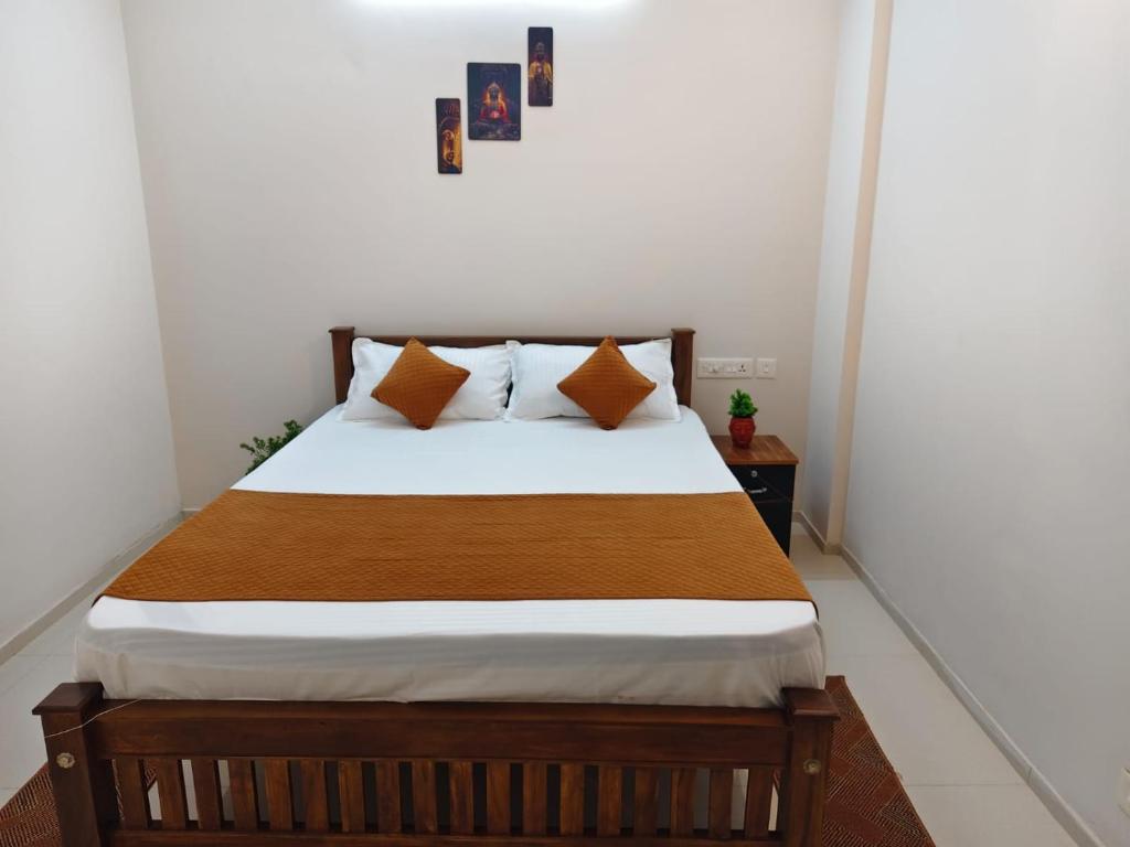 a bedroom with a bed with white sheets and orange pillows at Palazhi Stay 160m from Guruvayur Temple in Guruvāyūr