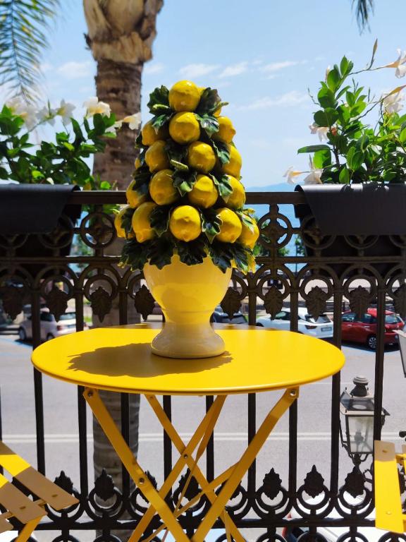 a yellow vase with a bunch of fruit on a table at La belle èpoque in Milazzo