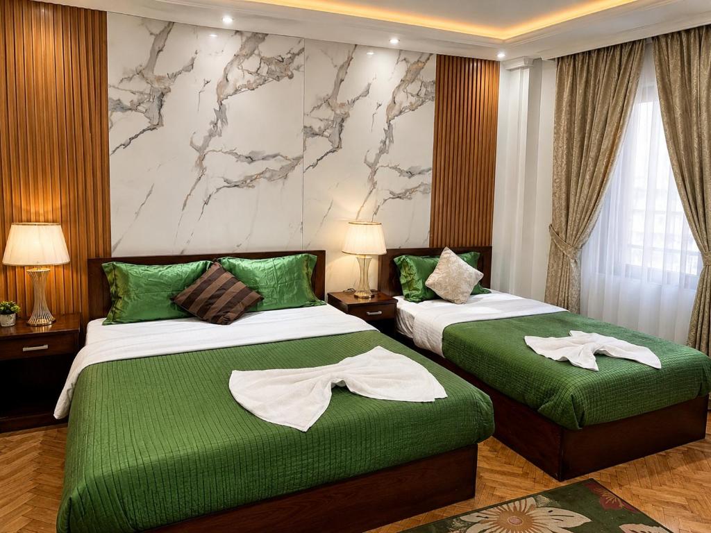a hotel room with two beds with green sheets at Downtown Inn in Cairo