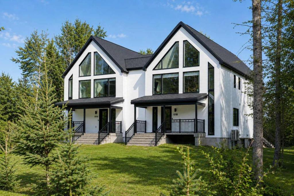 a white house with a black roof at Spa - River - Game Room - Le Belvedere in Mont-Tremblant