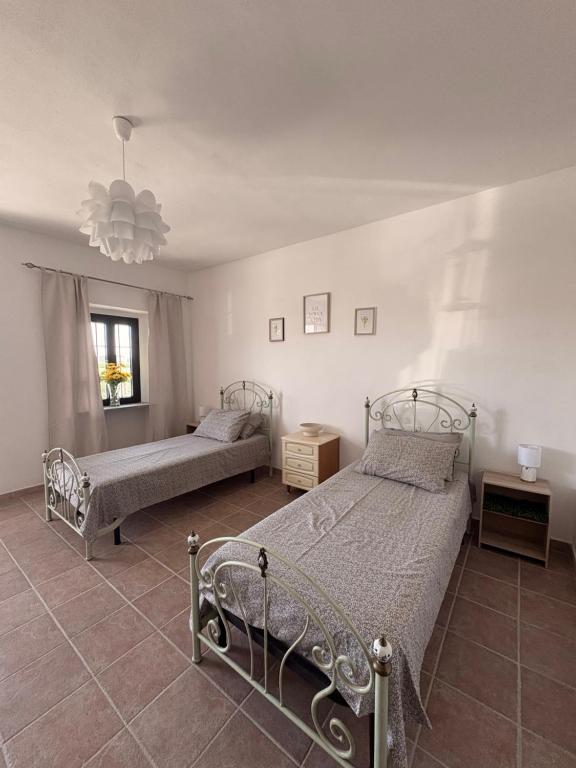 a bedroom with two beds and a chandelier at Cascina Tesoriera in Santhià