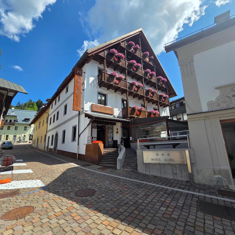 ein Gebäude mit einem Balkon, der mit Blumen bedeckt ist in der Unterkunft Hotel Raibl e Appartamenti in Tarvis
