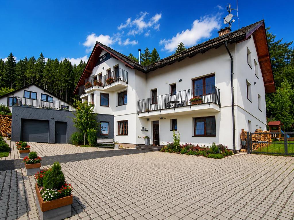 a large white house with a brick driveway at Úpatí Ještědu - apartmány in Liberec