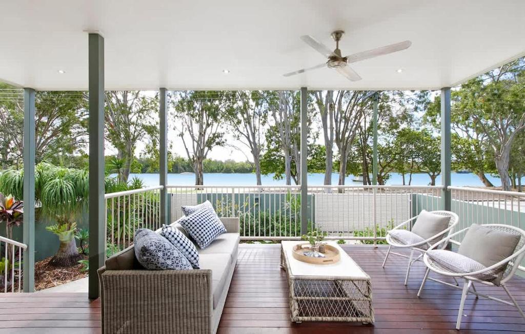 a porch with a couch and chairs and an umbrella at Tranquil & Modern Riverside Getaway in Noosaville