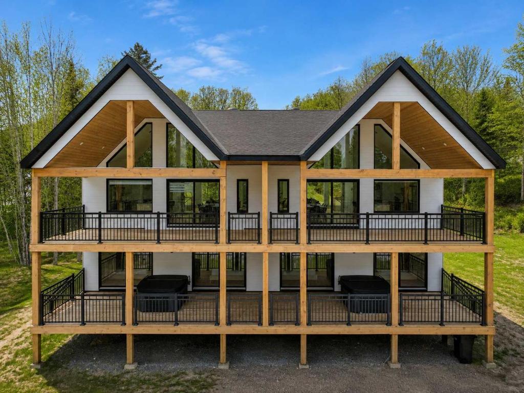 a house with a large deck with chairs on it at Spa - River - Game Room - Le Boreal in Mont-Tremblant