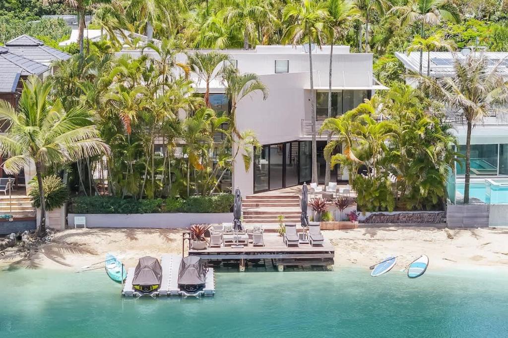 a house on the beach with a dock in the water at Luxury Retreat with Private Beach & Jetty in Noosa Heads