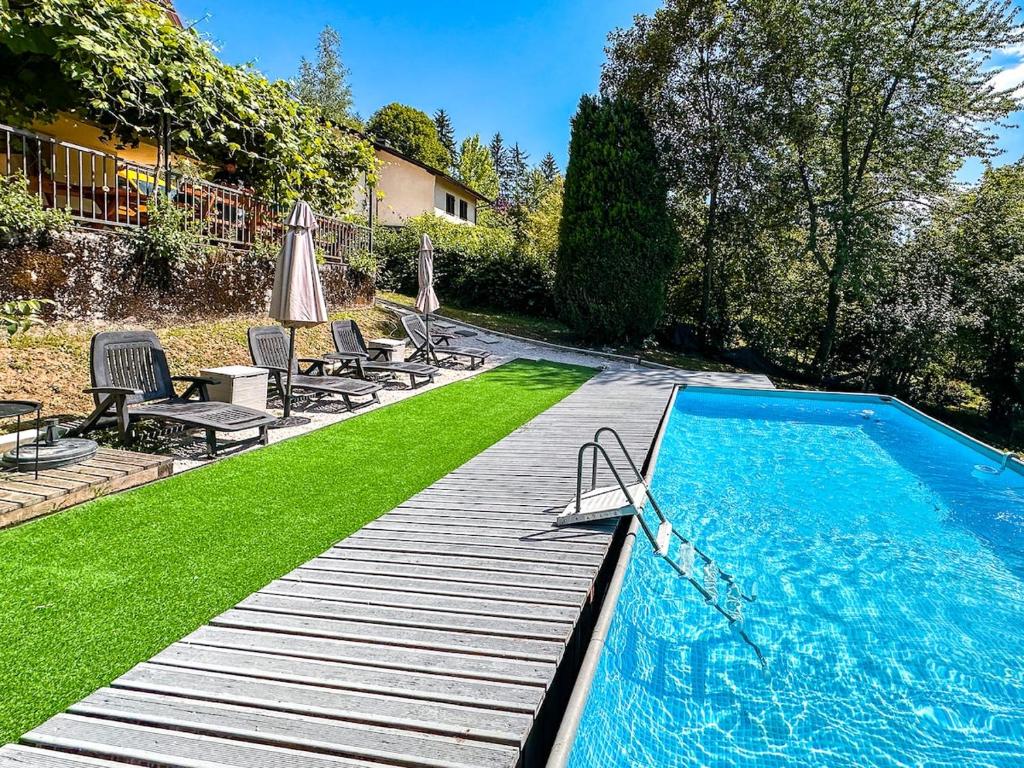 a swimming pool with green grass next to a house at Papa's Hideout Sarajevo in Buhotina