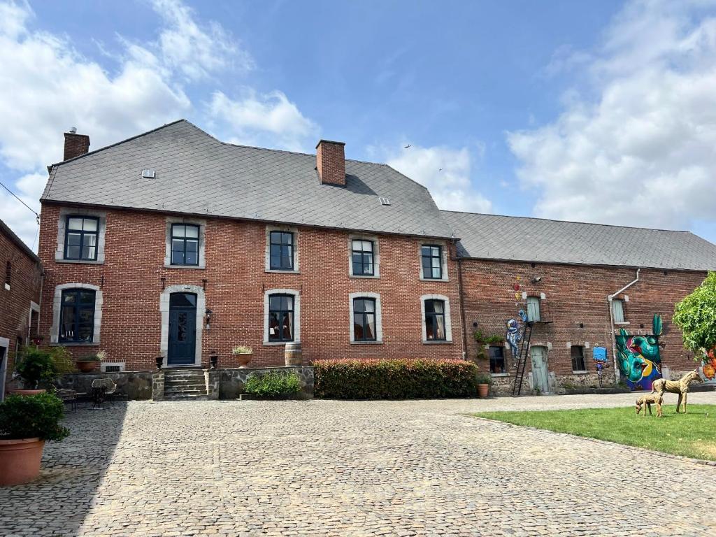 a large brick building with a dog in front of it at B&B Petit-Hallet in Hannut