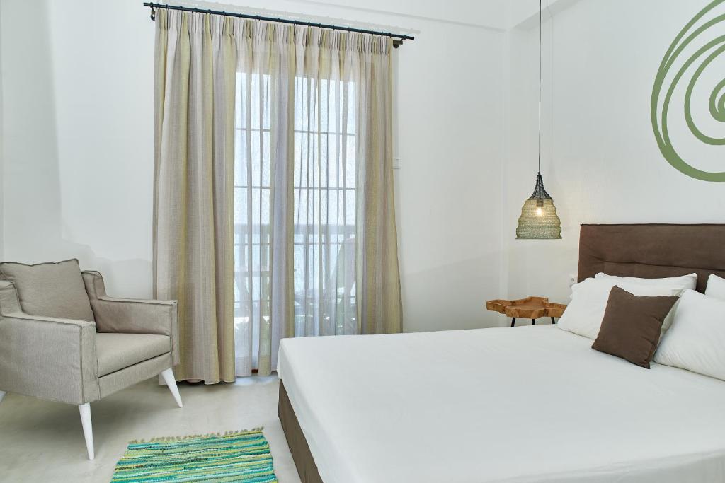 a bedroom with a large white bed and a chair at Kelly Hotel Agios Ioannis Pelion in Agios Ioannis Pelio