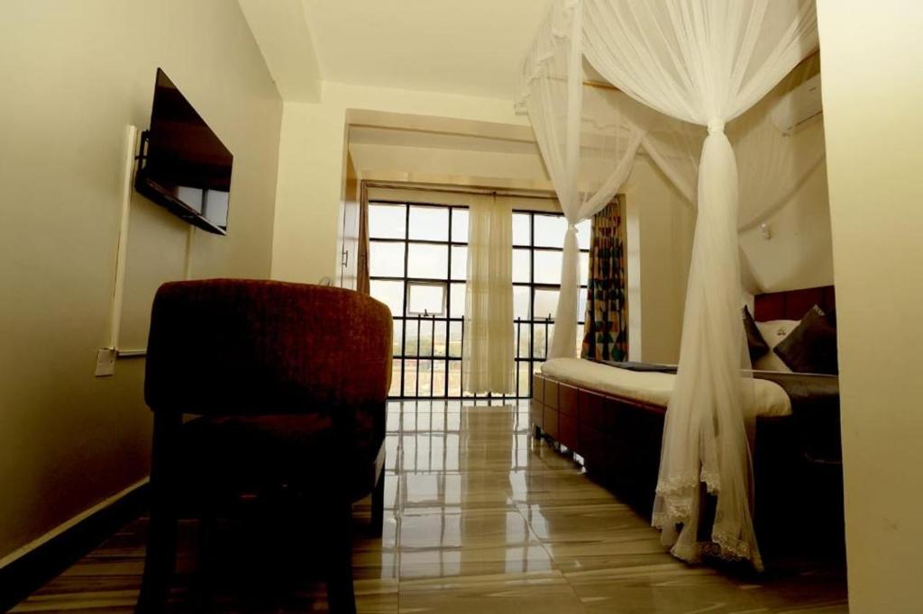 a bedroom with a bed and a chair and a window at KH KH Hotel in Kasese
