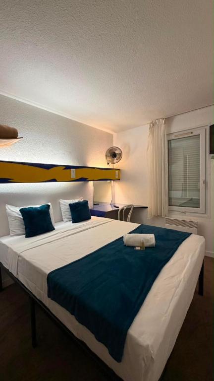 a bedroom with a large bed with blue sheets at hôtel du grand sud in Ramonville-Saint-Agne