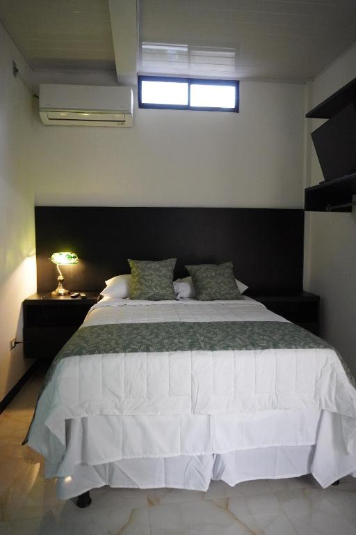 a bedroom with a large white bed with a window at Hotel Makao in La Rosita
