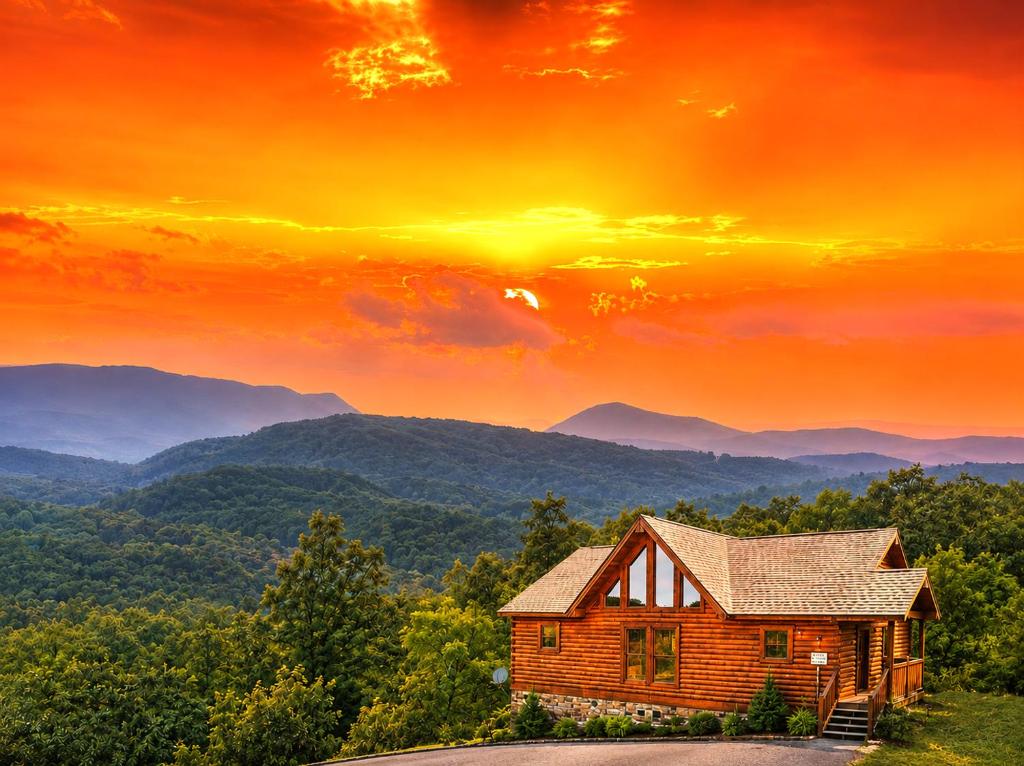 a cabin in the mountains with a sunset in the background at Pure Mountain Pleasure in Sevierville