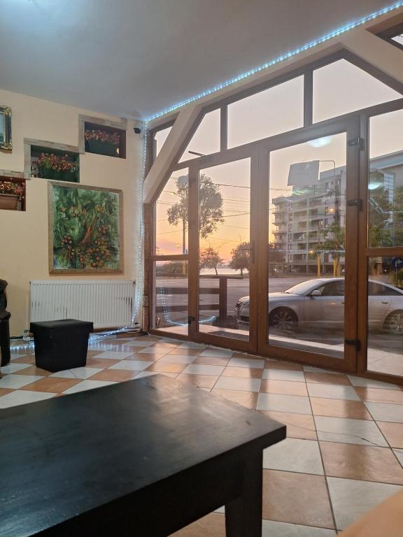 a living room with a table and a large window at Hotel Dona in Mamaia