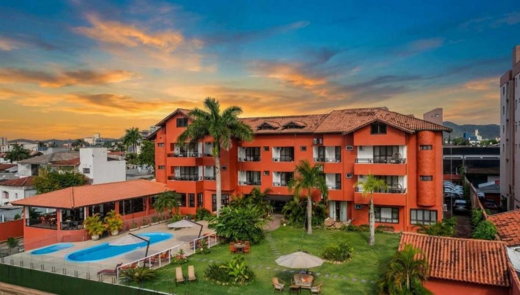 an orange apartment building with a swimming pool at Rizzu Marina Hotel in Balneário Camboriú
