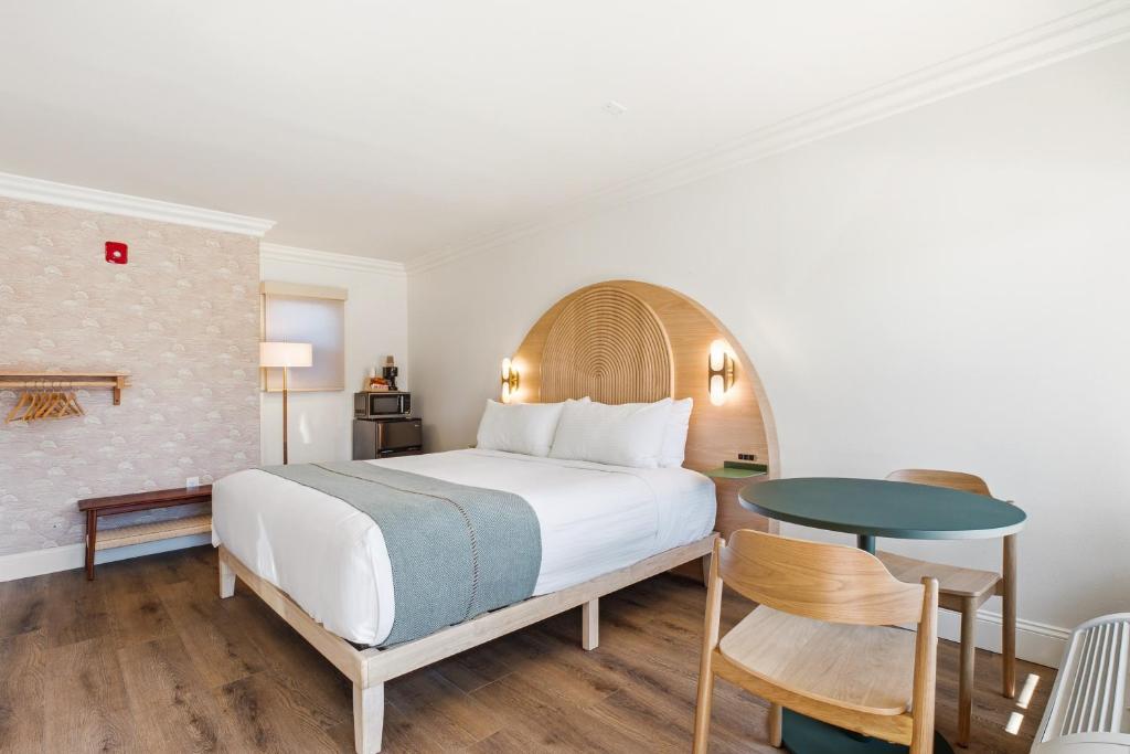 a bedroom with a large bed and a table at Sunset Motel in Santa Barbara