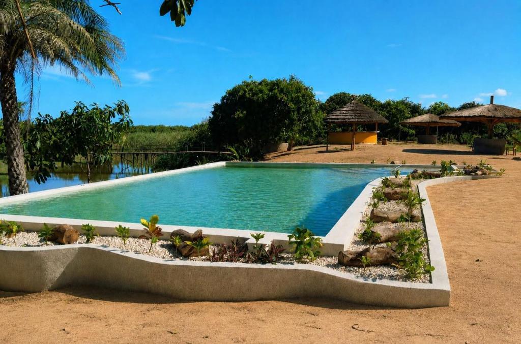 a swimming pool in the middle of a resort at JAC Tropical Lodge - Bar, Restaurant, Piscine, Massages, Plage, Nature, Excursions - Ressourcement et paix dans un paradis naturel et de confort les pieds dans l'eau - Respirez, vous êtes chez JAC - Navettes privées Banjul Aéroport in Diana
