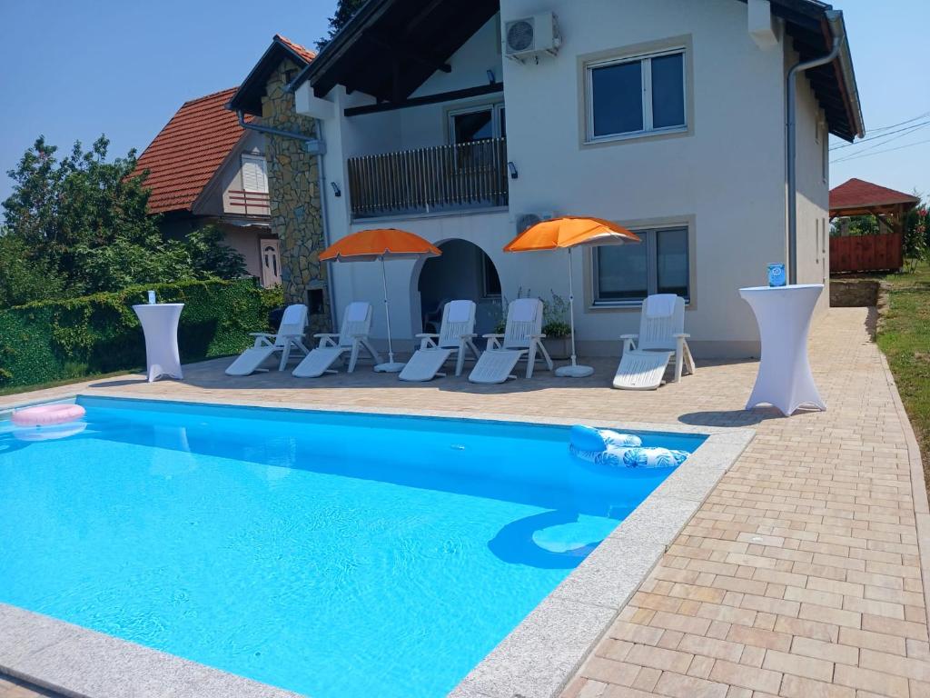 a swimming pool with chairs and umbrellas in front of a house at Villa Bavaria in Ritopek
