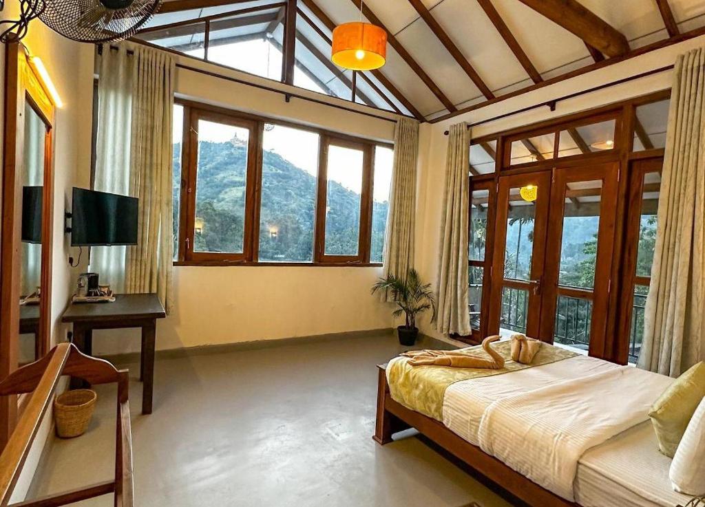 a bedroom with a bed and a desk and windows at Ella Scenic Heights in Ella