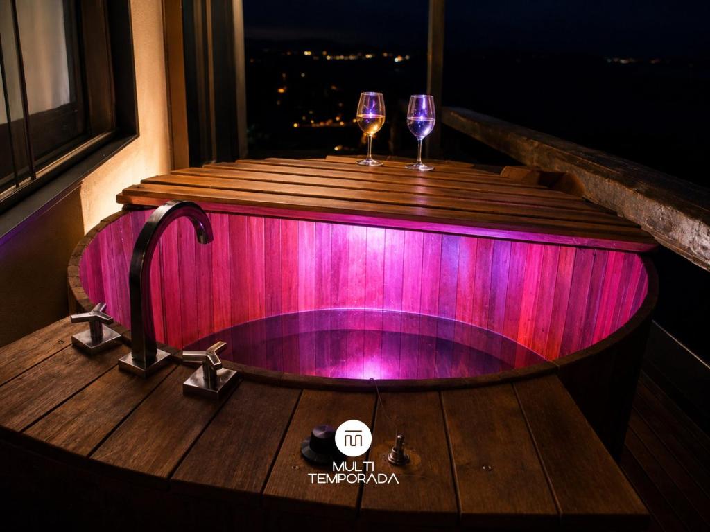a bath tub with two glasses of wine in it at Refugio Marincek - Gonçalves - MG in Gonçalves