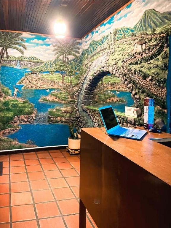 a laptop sitting on a desk in front of a mural at Hotel Cacique in Socorro